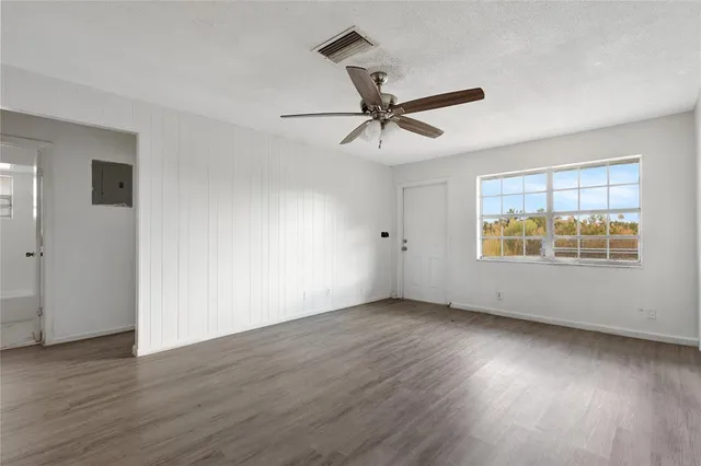 a view of an empty room with wooden floor and a window