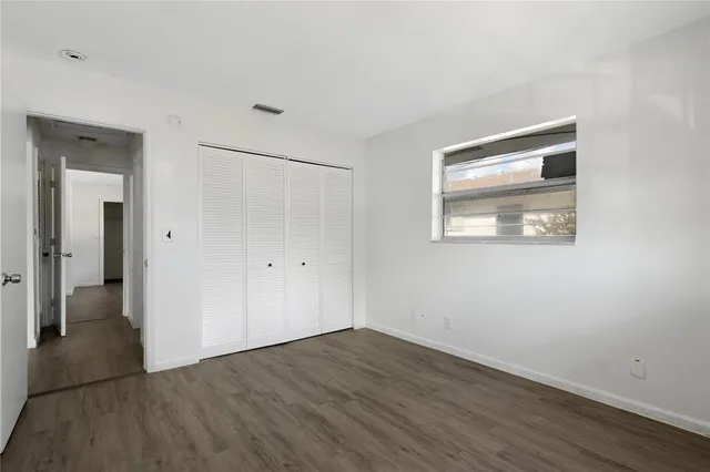 a view of an empty room with wooden floor and closet
