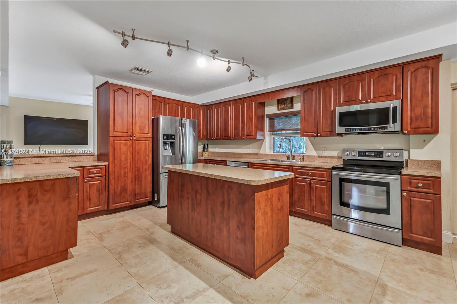 15101 Southwest 27th Street Davie, FL 33331 - Photo 12 of 100 a kitchen with stainless steel appliances wooden cabinets a stove top oven a sink and dishwasher