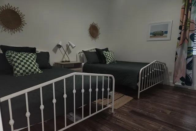 a bedroom with two beds and wooden floor