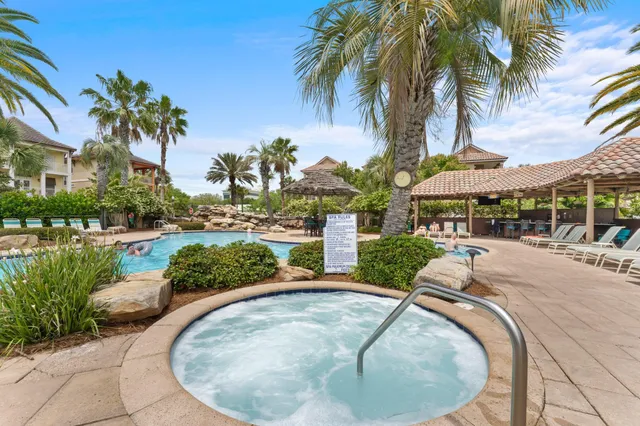 a view of a swimming pool with a table and chairs under palm trees