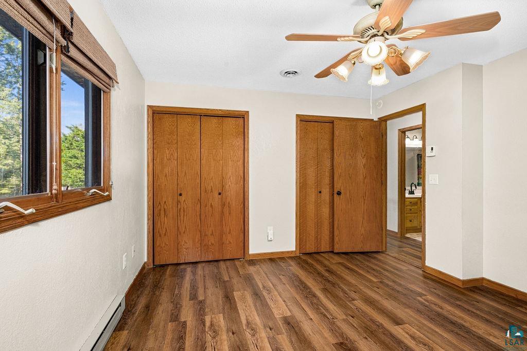5370 Ugstad Road Hermantown, MN 55811 - Photo 22 of 68 Wood-finish flooring, two sets of bi-fold closet doors, a ceiling fan with integrated lighting, and a window with wood-frame trim