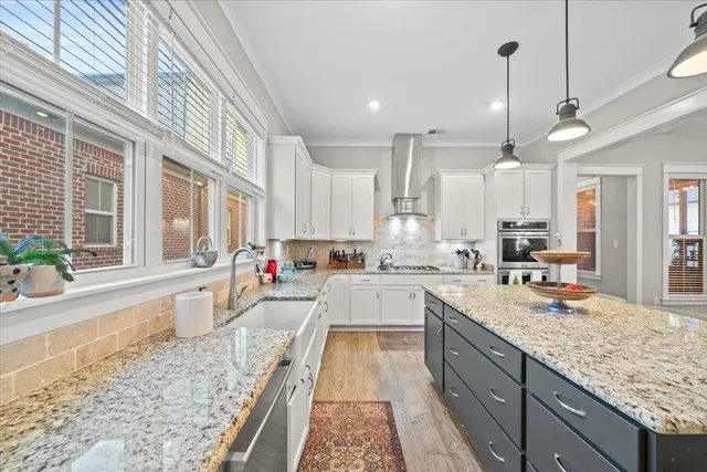 a large kitchen with granite countertop lots of counter space wooden floor and stainless steel appliances