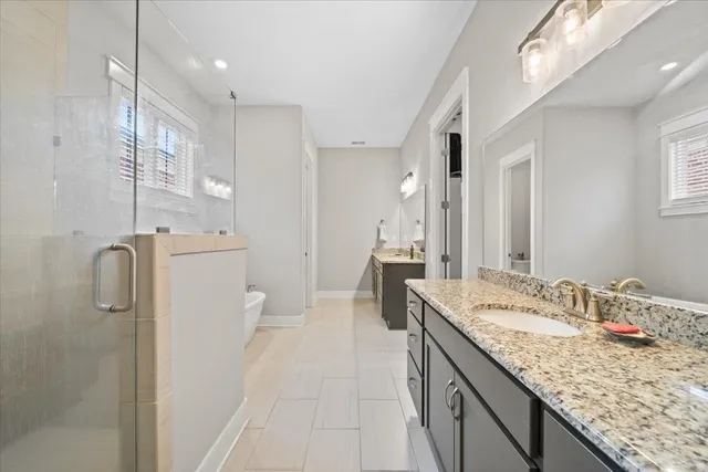a bathroom with a granite countertop double vanity sink a mirror and a shower