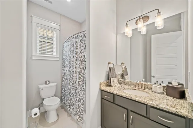 a bathroom with a granite countertop sink a toilet and a mirror
