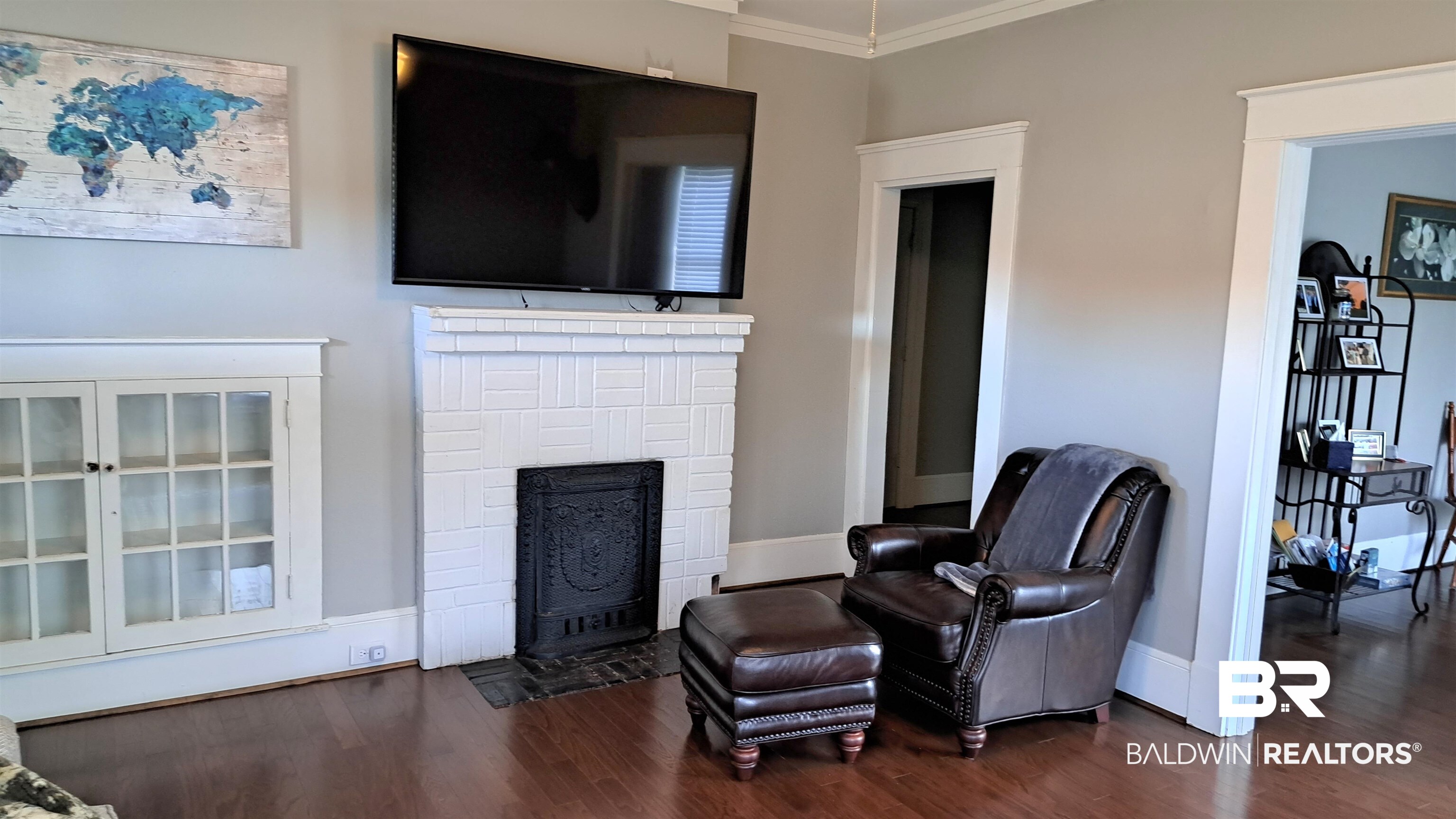 110 South Main Street Evergreen, AL 36401 - Photo 5 of 27 Hardwood-finish flooring complementing a white tile fireplace with a decorative cast-iron insert