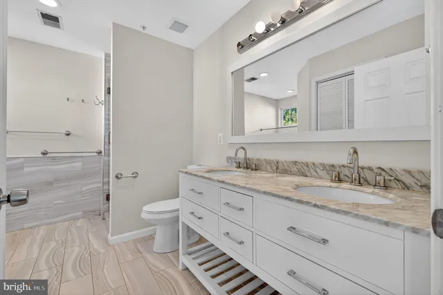 a bathroom with a granite countertop double vanity sink mirror and toilet