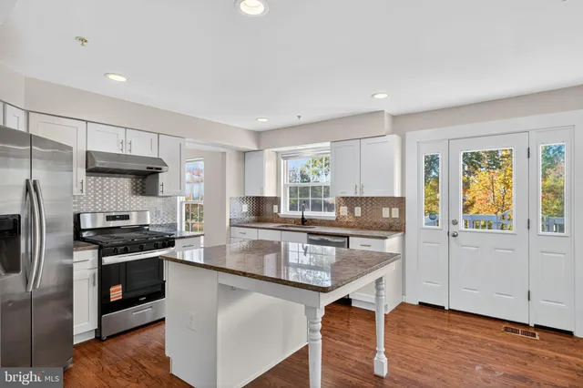 a kitchen with granite countertop a stove refrigerator and microwave