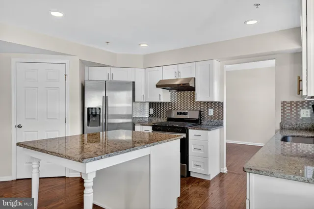 a kitchen with granite countertop a stove refrigerator and microwave
