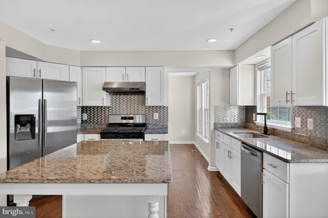 a kitchen with stainless steel appliances granite countertop a sink a stove and a refrigerator