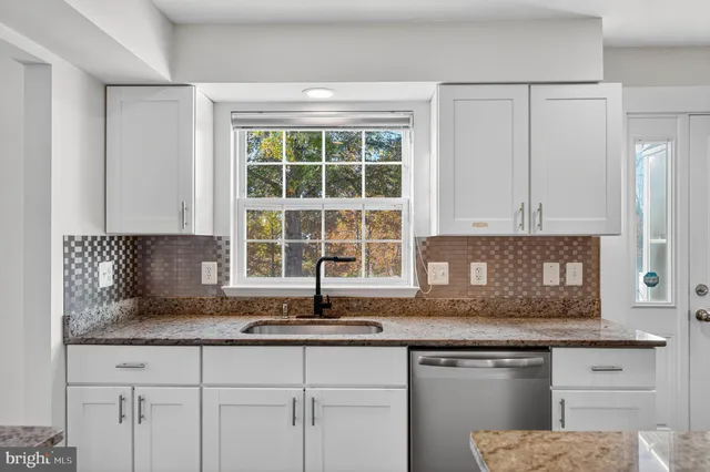 a kitchen with granite countertop a sink and a white wooden cabinets