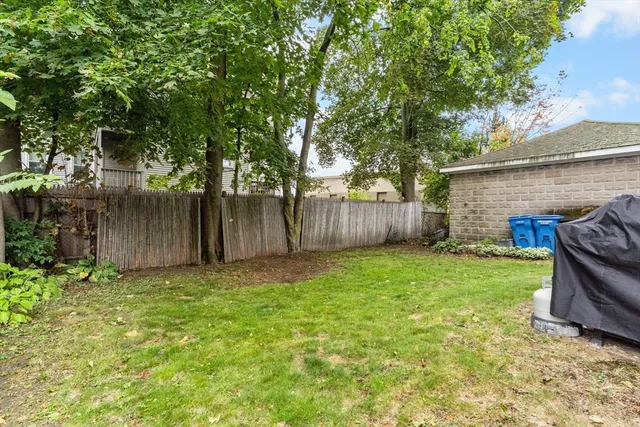 a view of a backyard with large trees and wooden fence