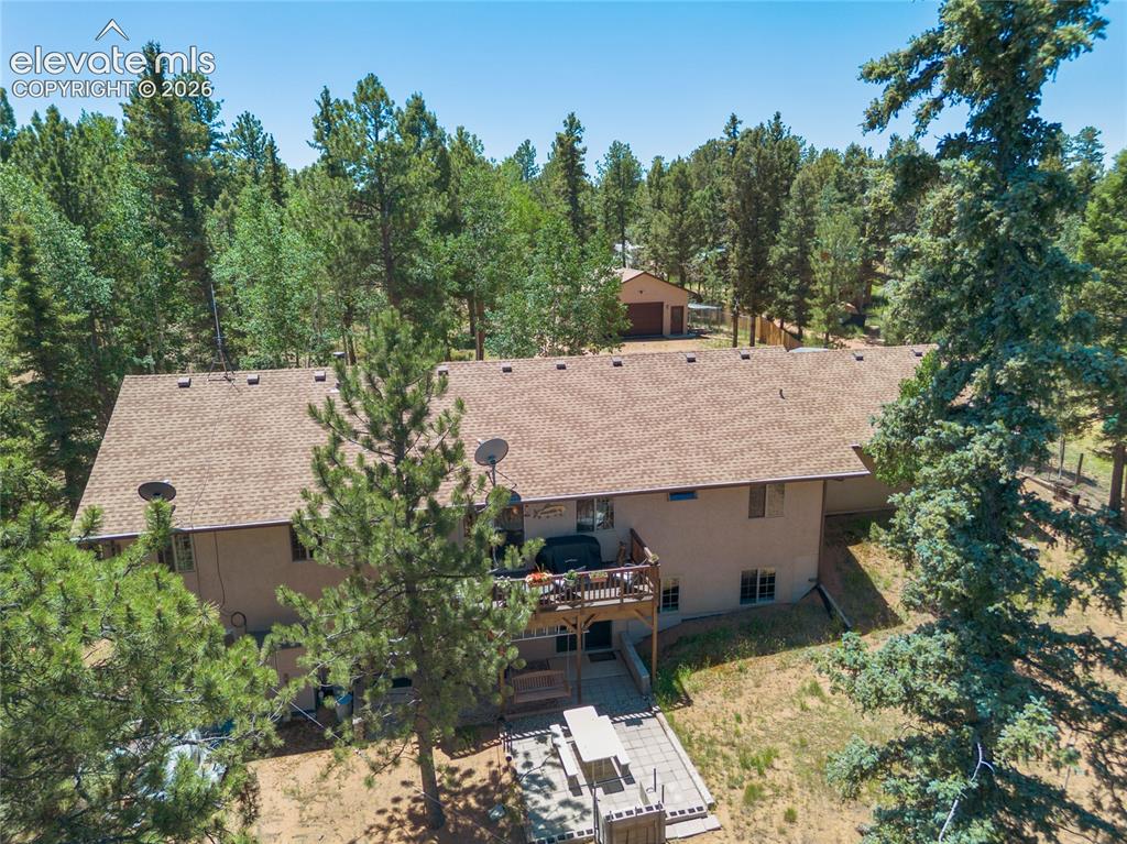657 Spring Valley Drive Divide, CO 80814 - Photo 42 of 43 Exterior featuring a multi-level structure with a brown shingle roof, a wood deck, and a ground-level patio