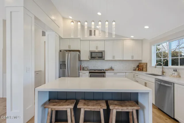 a kitchen with stainless steel appliances kitchen island a table chairs sink and cabinets