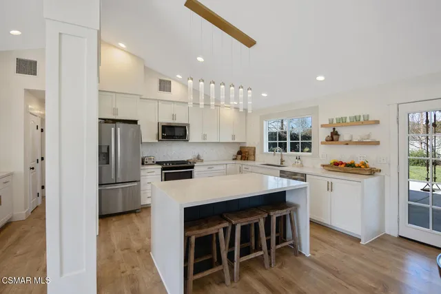 a kitchen with kitchen island a stove a sink a refrigerator and a cabinets
