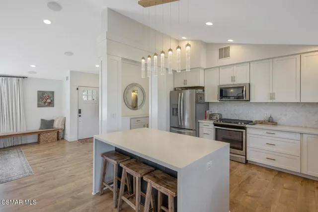 a room with kitchen island a chandelier and a view of living room