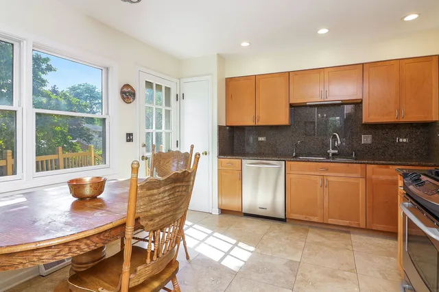 a kitchen with stainless steel appliances granite countertop a stove a sink a microwave a dining table and chairs