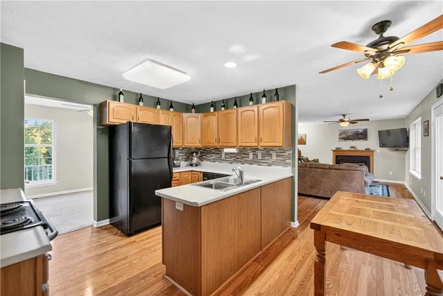 a kitchen with stainless steel appliances granite countertop a refrigerator a sink dishwasher a stove and a dining table with wooden floor