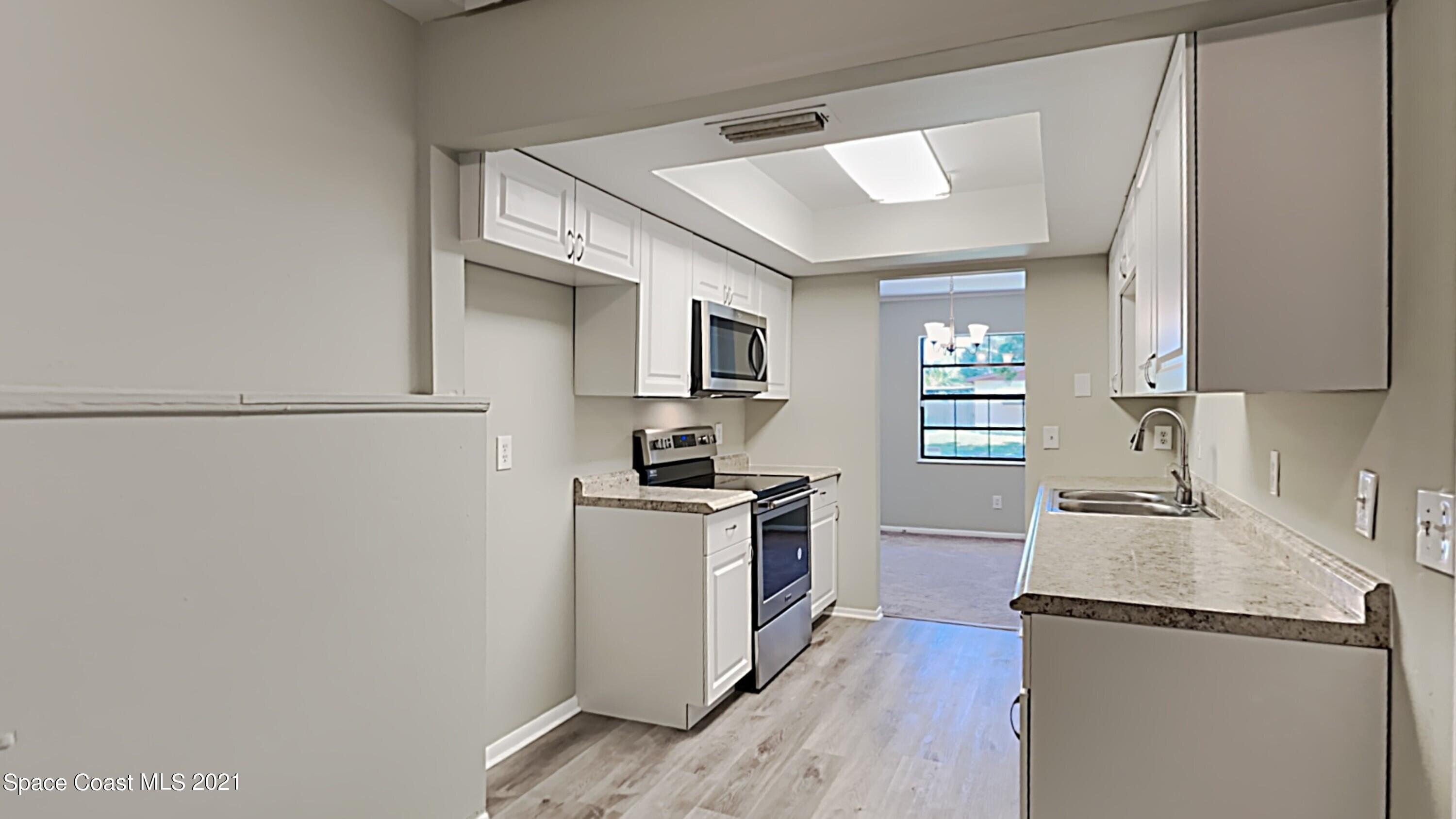 955 Lexington Road Rockledge, FL 32955 - Photo 7 of 18 a kitchen with granite countertop stainless steel appliances a refrigerator a stove top oven a sink and dishwasher