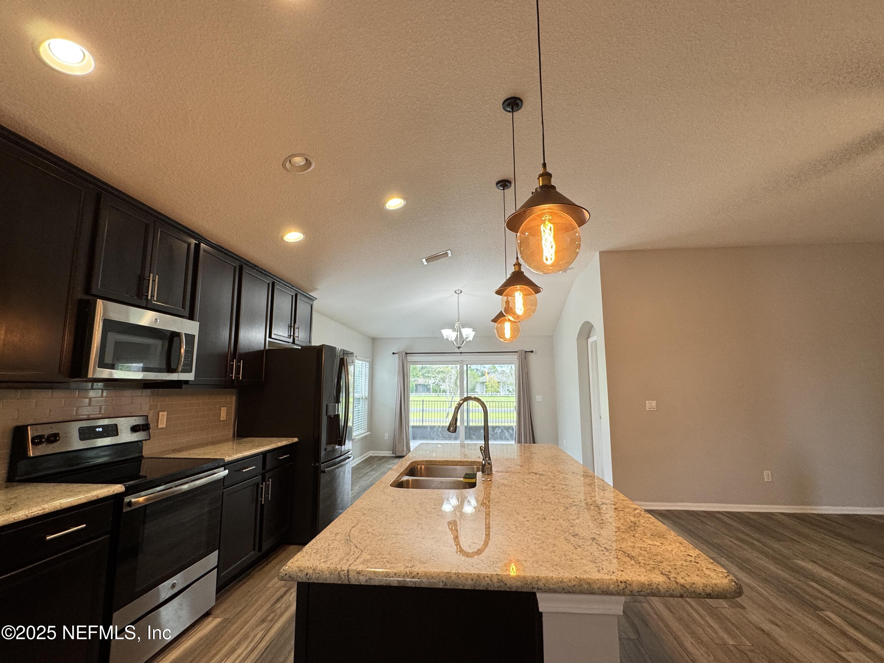 94267 Woodbrier Circle Fernandina Beach, FL 32034 - Photo 7 of 32 a kitchen with stainless steel appliances granite countertop a sink a stove and a wooden floors