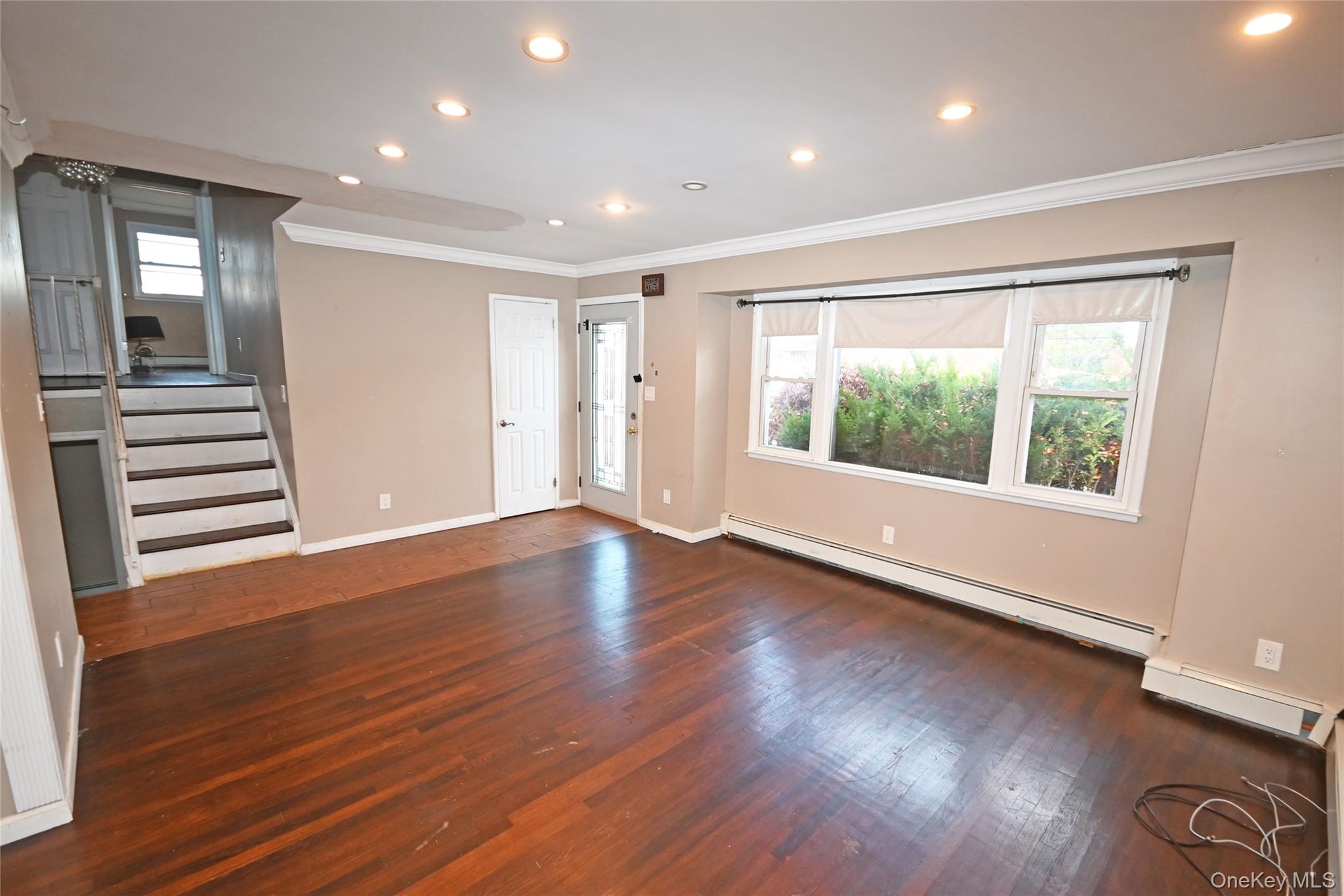 89 Osborne Road West Hempstead, NY 11552 - Photo 20 of 50 Unfurnished living room with stairs, ornamental molding, recessed lighting, dark wood-style flooring, and a baseboard heating unit