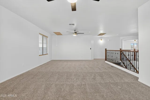 an empty room with ceiling fan and windows