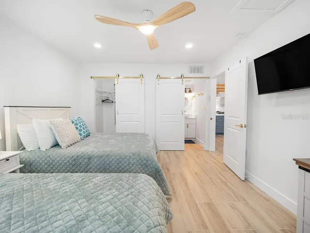 a spacious bedroom with a bed and a flat screen tv