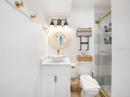 a bathroom with a toilet sink vanity and shower