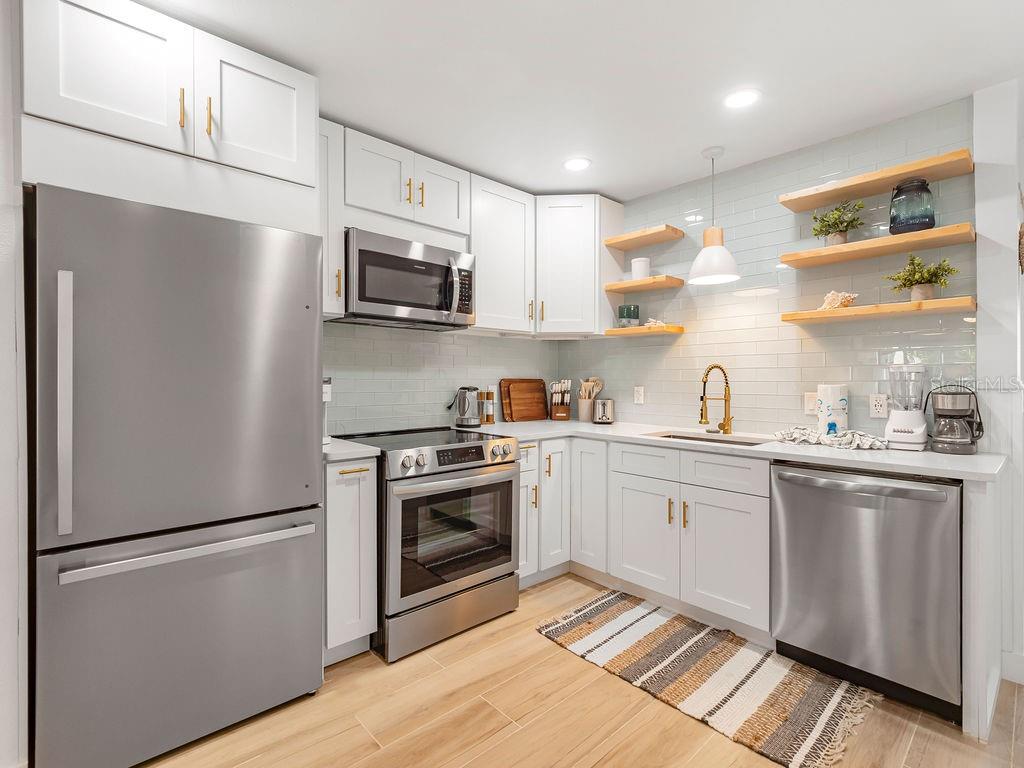 449 63rd Street Holmes Beach, FL 34217 - Photo 7 of 54 a kitchen with stainless steel appliances a refrigerator sink and microwave