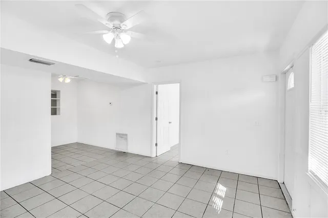 an empty room with windows and fan