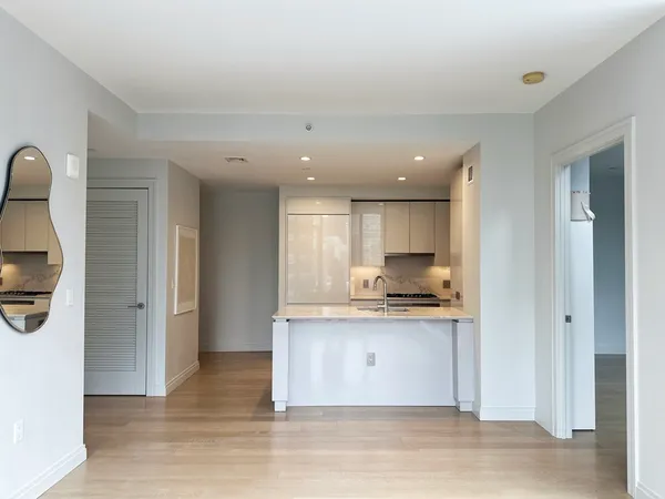 a living room with stainless steel appliances kitchen island granite countertop a refrigerator and a sink