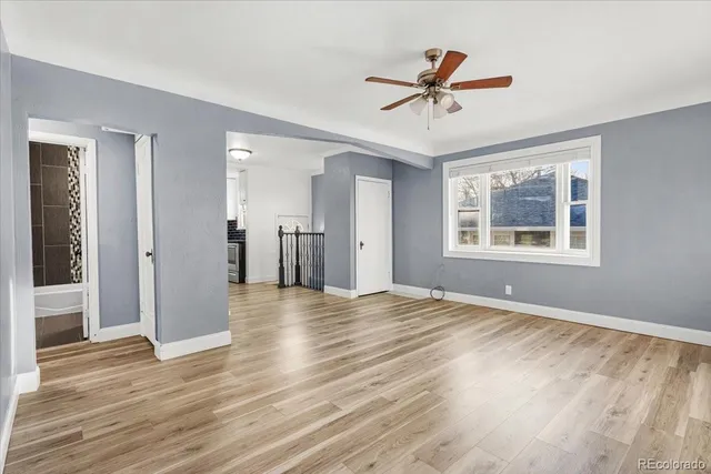 a view of empty room with wooden floor and ceiling fan