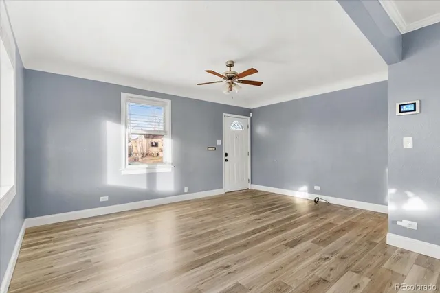 a view of an empty room with window and wooden floor