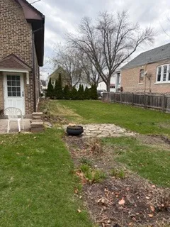 a view of a backyard with table and chairs potted plants and large tree