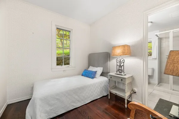a bedroom with a bed a lamp and wooden floor