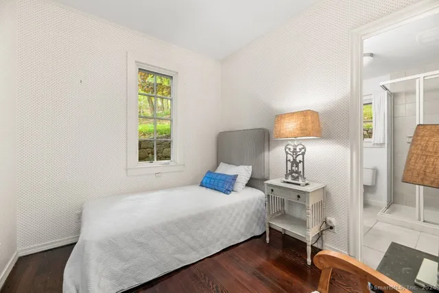 a bedroom with a bed a lamp and wooden floor