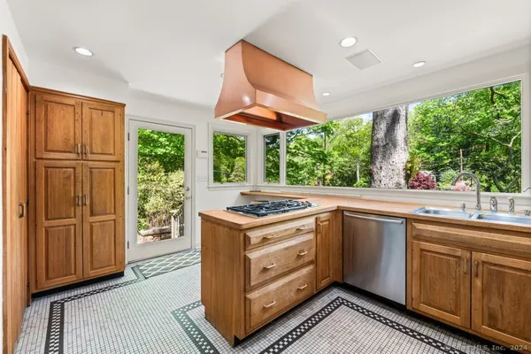 a kitchen with a stove a sink a window and wooden cabinets