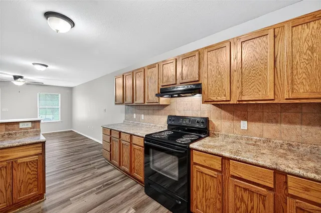 a kitchen with granite countertop wooden cabinets stainless steel appliances and a window