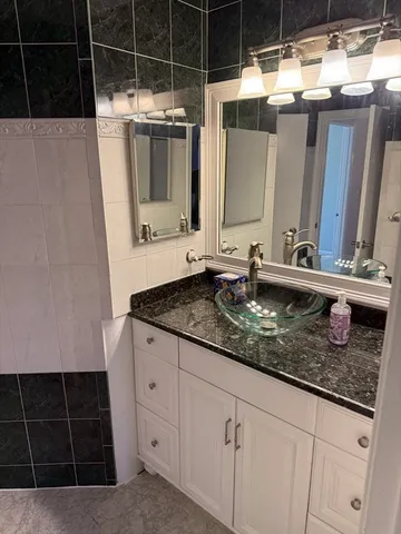 a bathroom with a granite countertop sink a mirror and shower