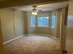 a view of an empty room with window and chandelier fan