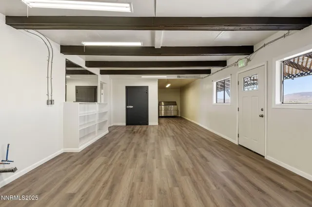 a view of an empty room with a window and wooden floor