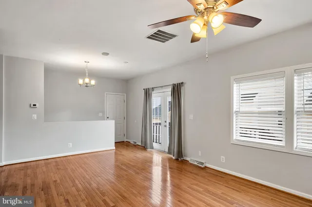 a view of an empty room with window and wooden floor