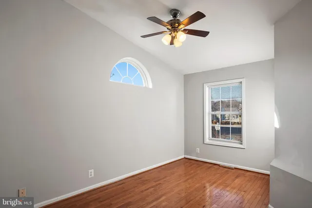an empty room with windows and ceiling fan