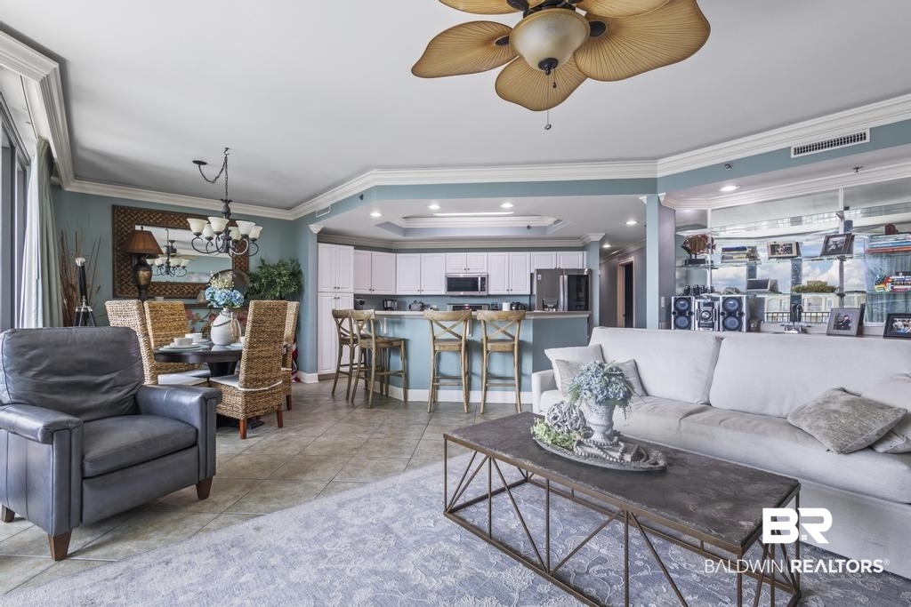 27582 Canal Road, Unit 2408 Orange Beach, AL 36561 - Photo 12 of 47 Tiled living room with ceiling fan with notable chandelier and crown molding