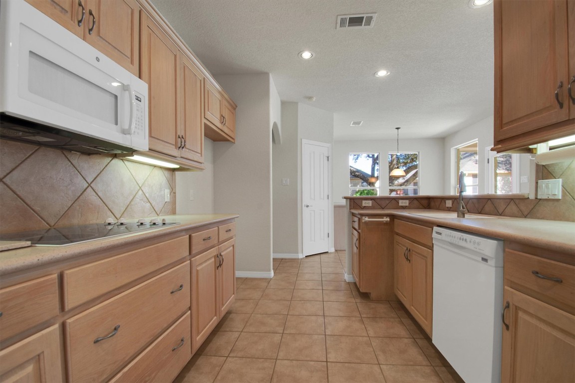 102 Lavaca Lane Georgetown, TX 78628 - Photo 11 of 23 a kitchen with stainless steel appliances granite countertop a sink and dishwasher a refrigerator with wooden cabinets