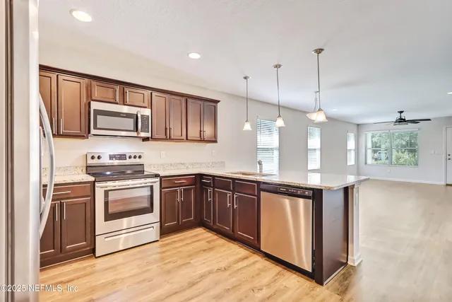 a kitchen with stainless steel appliances granite countertop a stove a sink and a microwave