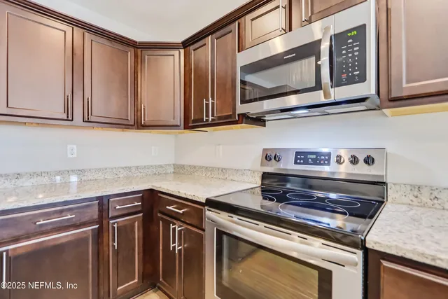 a kitchen with granite countertop a stove microwave and sink