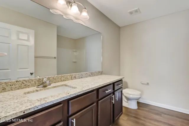 a bathroom with a granite countertop sink a toilet and a mirror
