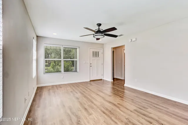 an empty room with wooden floor and windows