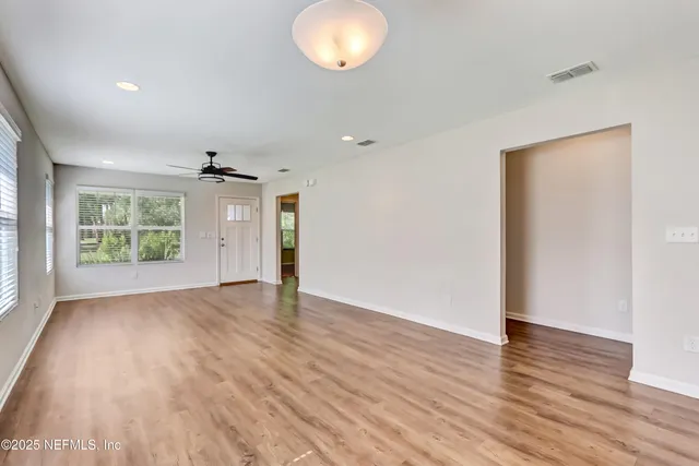 an empty room with wooden floor and windows